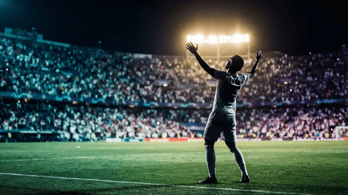Football player silhouette celebrating in white kit under dramatic stadium lights