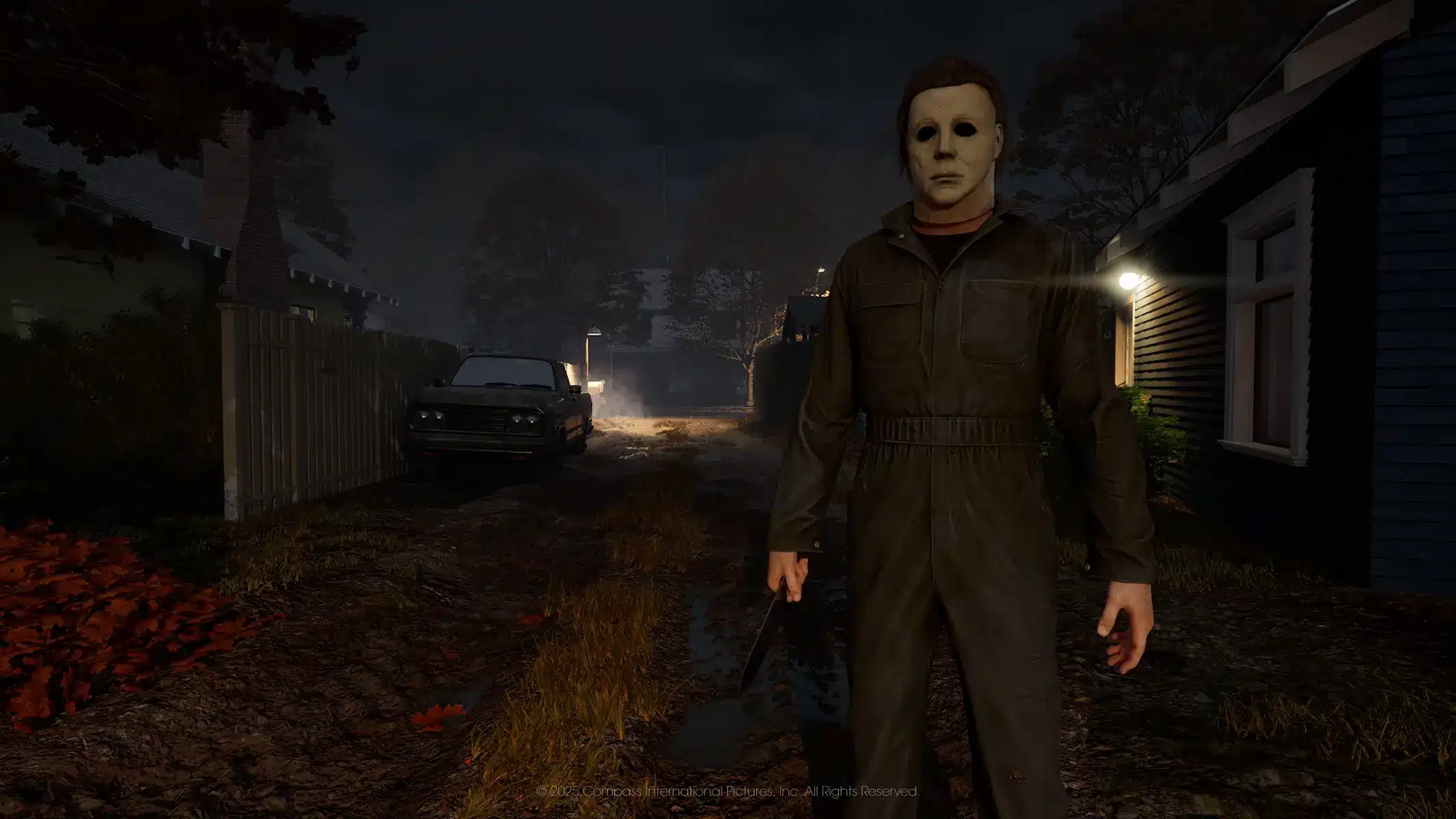 Michael Myers wearing a mask and jumpsuit standing in a dark residential street at night