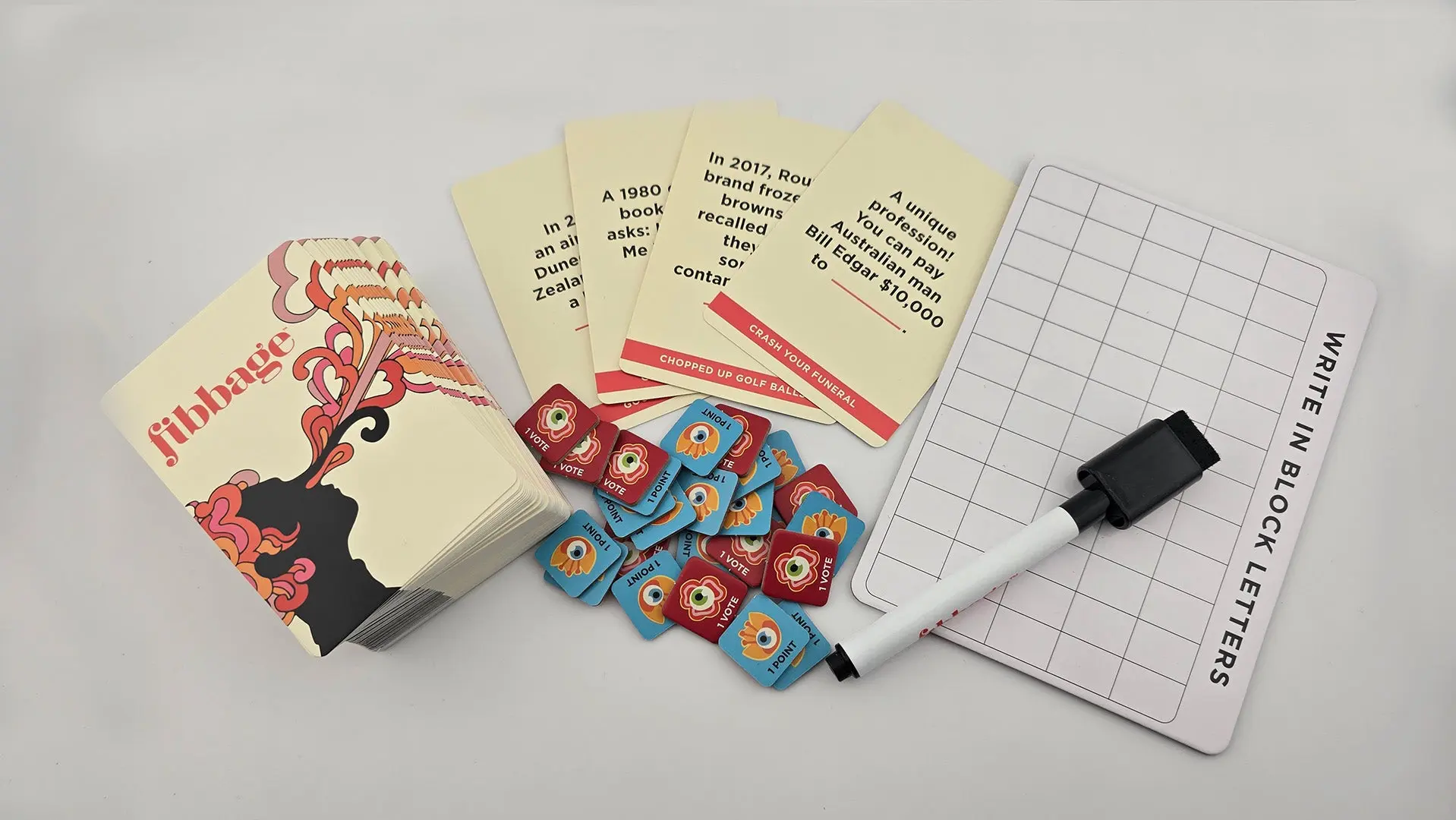 Fibbage card game components including a deck of cards, red and blue point tokens, a whiteboard, and a marker.