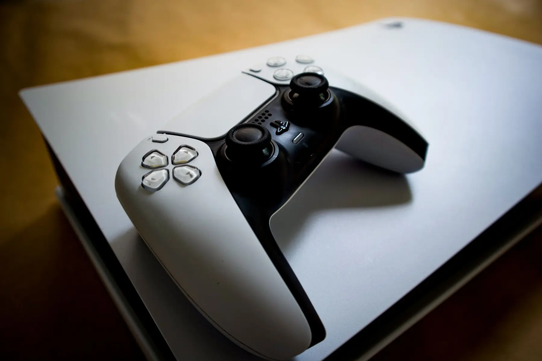 A white PlayStation 5 DualSense controller resting on top of a PS5 console.